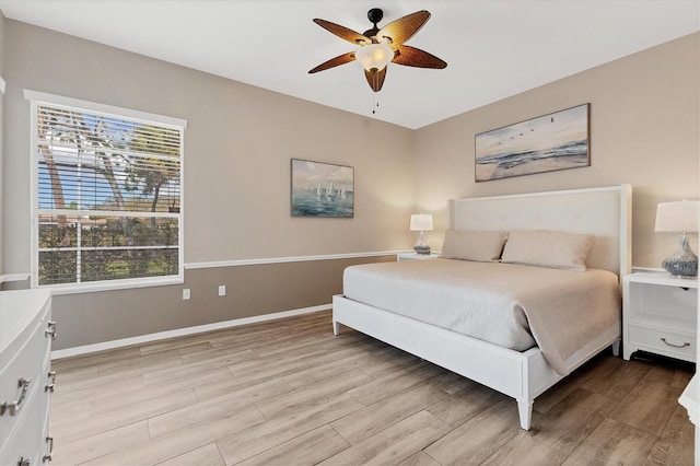 bedroom featuring a ceiling fan, light wood-style flooring, and baseboards