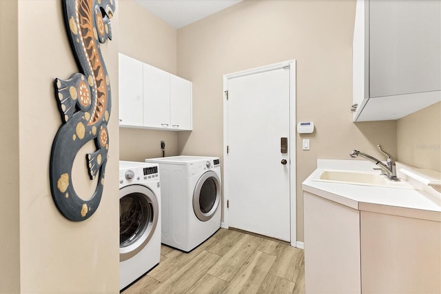 washroom with light wood finished floors, a sink, cabinet space, and washer and dryer