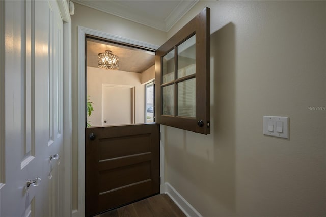 doorway featuring baseboards, dark wood-type flooring, and crown molding