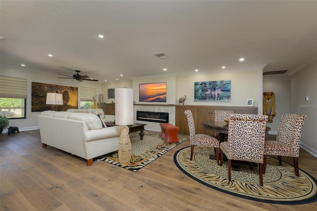 living area with recessed lighting, a premium fireplace, wood finished floors, baseboards, and ornamental molding