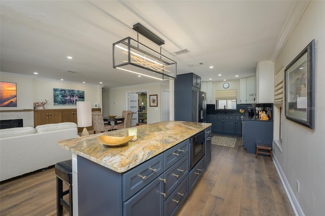 kitchen featuring dark wood-type flooring, a kitchen island, stainless steel fridge, and crown molding