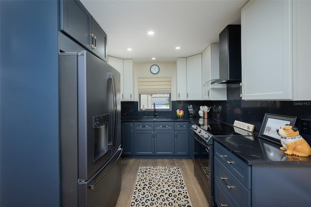 kitchen featuring black / electric stove, dark countertops, a sink, stainless steel fridge, and wall chimney exhaust hood