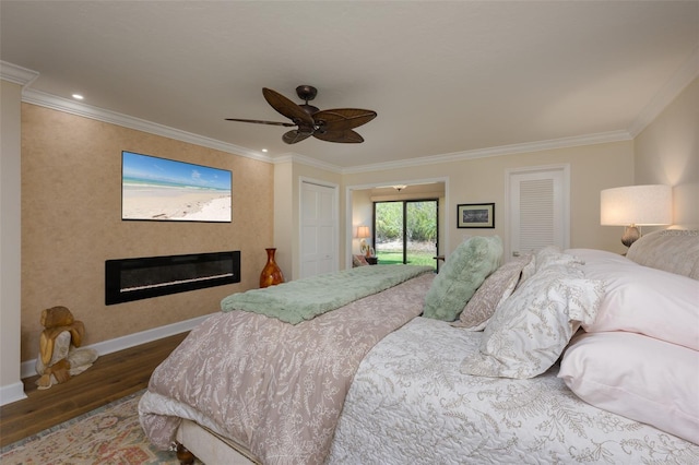 bedroom with wood finished floors, a glass covered fireplace, and crown molding