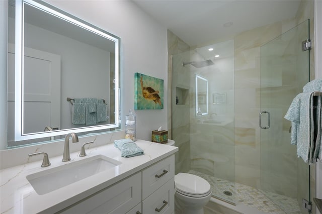 bathroom with a shower stall, toilet, and vanity