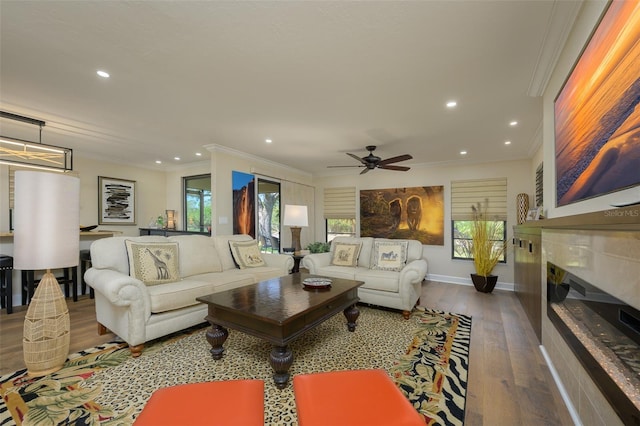 living room featuring ornamental molding, wood finished floors, a glass covered fireplace, and recessed lighting