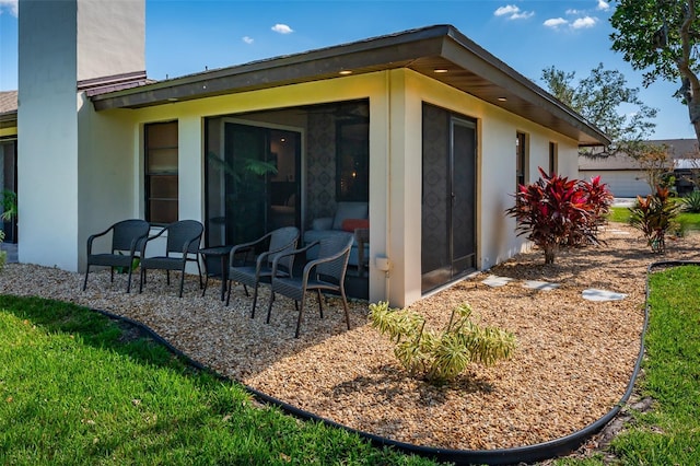 rear view of house with a sunroom and stucco siding