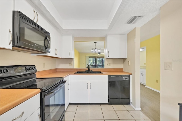 kitchen with white cabinets, hanging light fixtures, light countertops, black appliances, and a sink