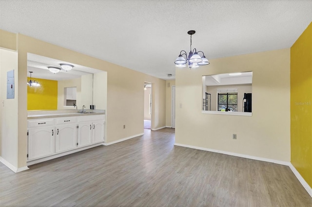 interior space with baseboards, light wood finished floors, a sink, and a notable chandelier