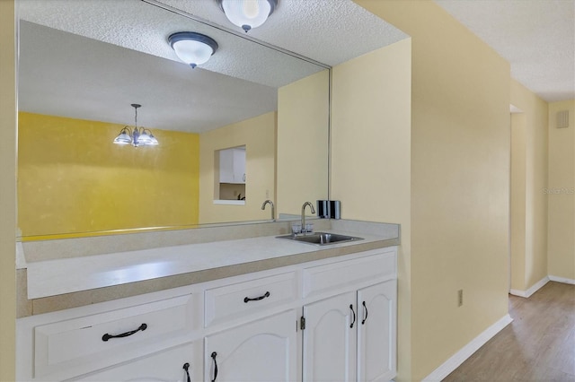 kitchen with decorative light fixtures, light countertops, white cabinetry, a sink, and a textured ceiling