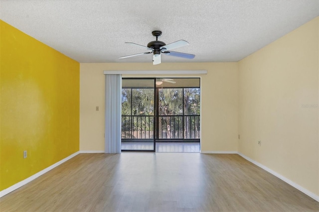 spare room featuring ceiling fan, light wood-style flooring, baseboards, and a textured ceiling