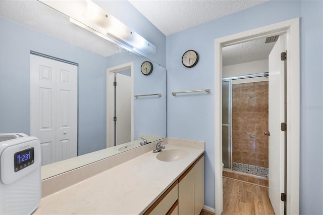 bathroom featuring a shower stall, vanity, a textured ceiling, and wood finished floors