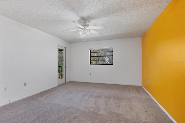 carpeted empty room featuring ceiling fan, a textured ceiling, and baseboards