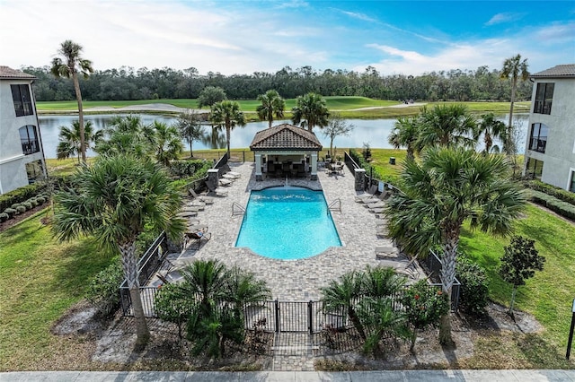 community pool with a water view, fence, and a patio