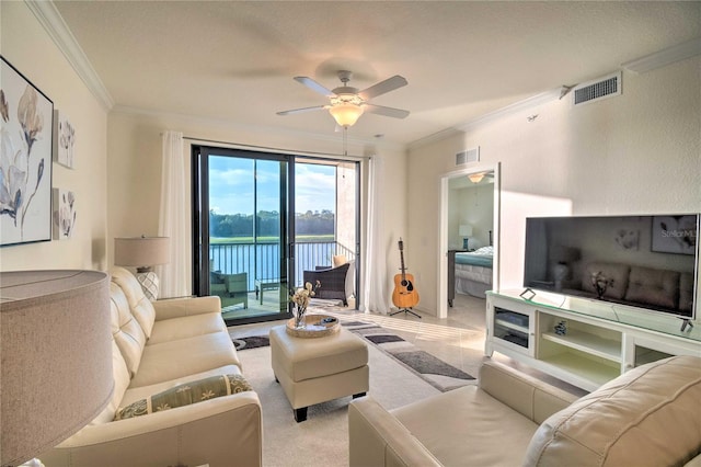 living room with ornamental molding, visible vents, and ceiling fan