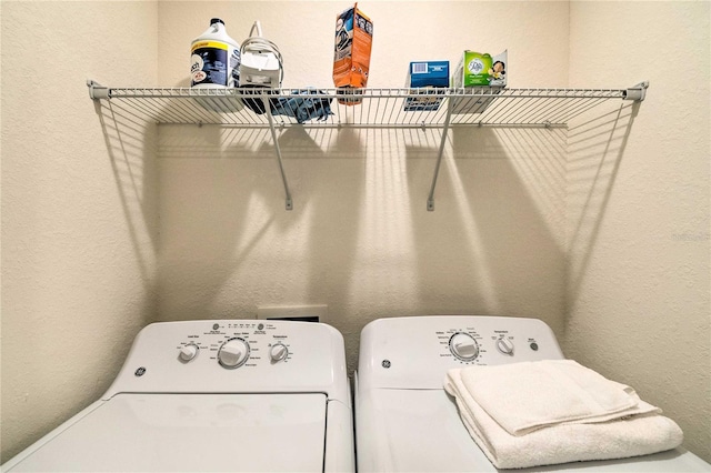 clothes washing area featuring a textured wall, laundry area, and washing machine and dryer