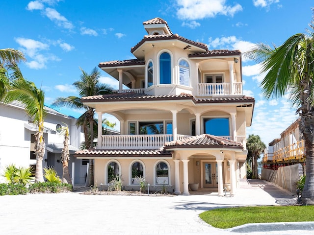 mediterranean / spanish-style home featuring driveway, fence, a balcony, and stucco siding