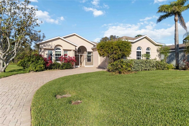 view of front facade featuring a front lawn, decorative driveway, and stucco siding