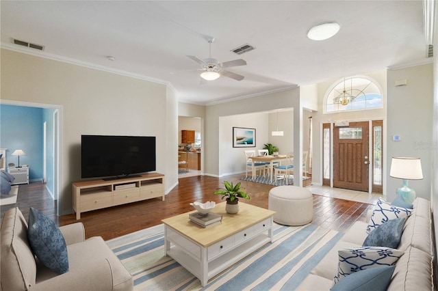 living area with visible vents, crown molding, and wood finished floors