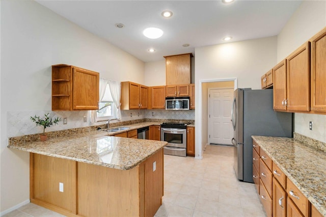 kitchen with decorative backsplash, light stone counters, a peninsula, stainless steel appliances, and a sink