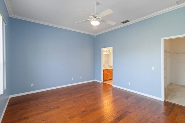 unfurnished bedroom featuring crown molding, a closet, visible vents, wood-type flooring, and baseboards