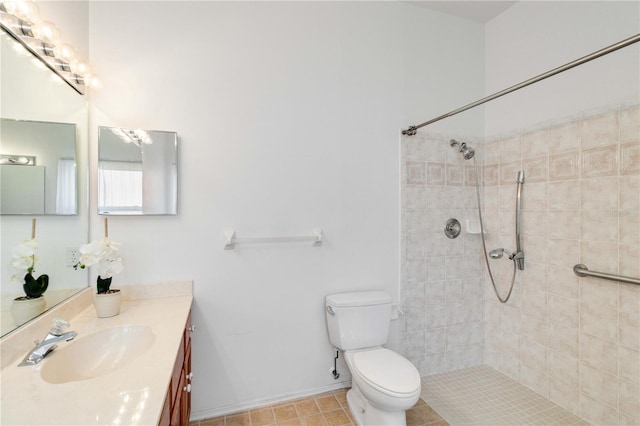 bathroom featuring vanity, a tile shower, toilet, and baseboards