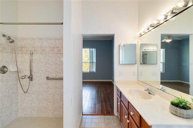 bathroom featuring a ceiling fan, tiled shower, and vanity