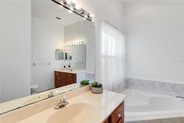 full bath featuring toilet, a garden tub, and vanity