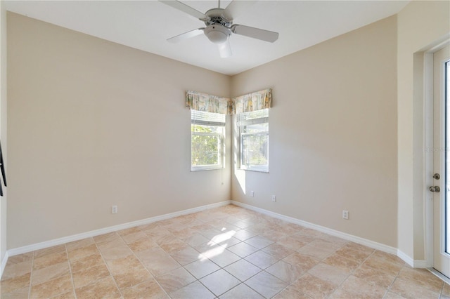 spare room with a ceiling fan and baseboards