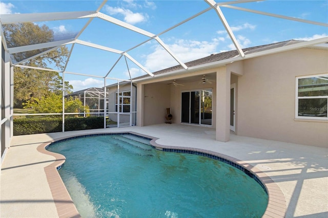 pool with a patio area, glass enclosure, and a ceiling fan