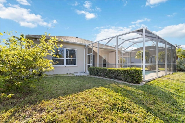 back of house with a yard, an outdoor pool, a lanai, and stucco siding