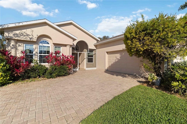 ranch-style house featuring decorative driveway, an attached garage, and stucco siding