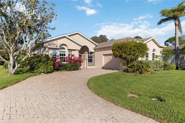 ranch-style home with a garage, decorative driveway, a front yard, and stucco siding