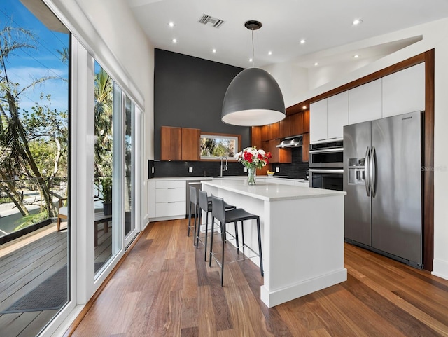 kitchen featuring appliances with stainless steel finishes, modern cabinets, a center island with sink, and white cabinets