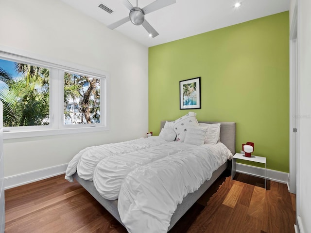 bedroom featuring visible vents, ceiling fan, baseboards, and wood finished floors