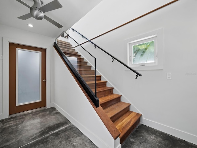 stairway with ceiling fan, recessed lighting, unfinished concrete flooring, and baseboards