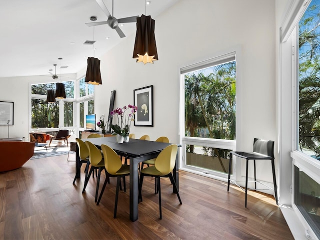 dining space featuring ceiling fan, a high ceiling, visible vents, and wood finished floors