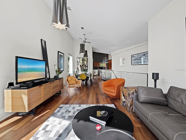 living area with a towering ceiling, visible vents, and wood finished floors