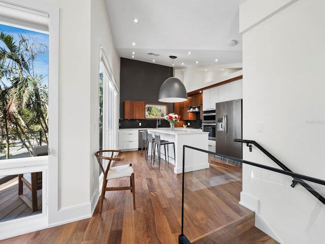 kitchen featuring appliances with stainless steel finishes, a kitchen island with sink, white cabinetry, and a breakfast bar