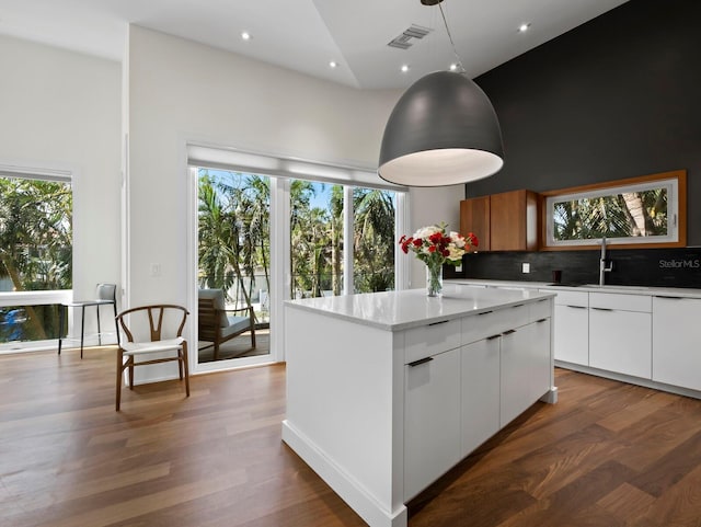 kitchen with visible vents, white cabinets, a center island, hanging light fixtures, and light countertops