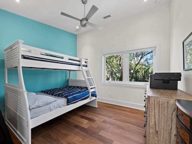 bedroom with a ceiling fan, wood finished floors, visible vents, and baseboards