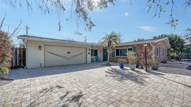 ranch-style home featuring a garage, decorative driveway, and brick siding