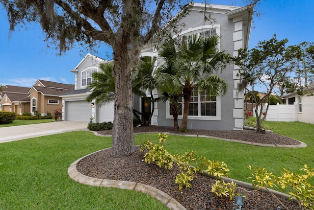 view of front of home with a garage, concrete driveway, fence, a front yard, and stucco siding