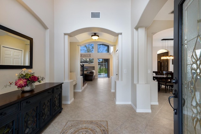 entryway with arched walkways, visible vents, baseboards, and light tile patterned floors