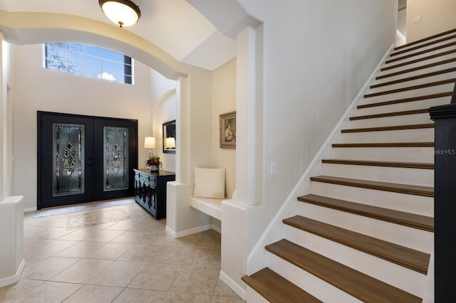 foyer entrance with french doors, light tile patterned flooring, baseboards, and stairs