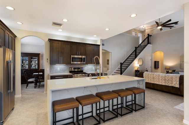 kitchen with visible vents, arched walkways, stainless steel appliances, and a sink