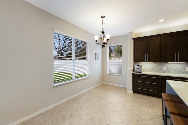 kitchen featuring baseboards, decorative light fixtures, light countertops, dark brown cabinets, and backsplash