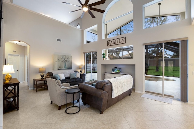 living area with arched walkways, light tile patterned floors, plenty of natural light, and visible vents