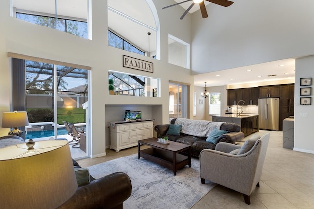 living area with light tile patterned floors, recessed lighting, baseboards, and ceiling fan with notable chandelier