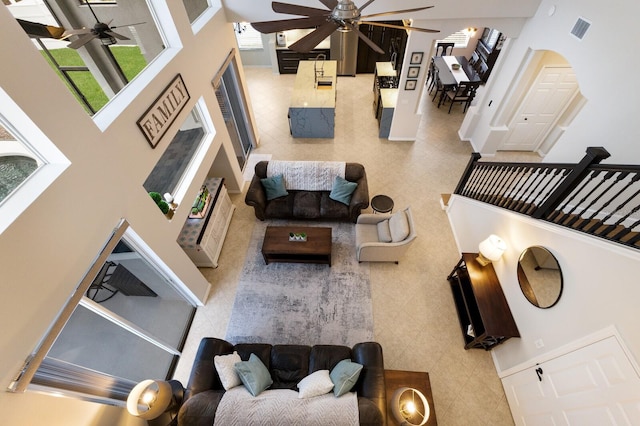 living area with visible vents, a towering ceiling, and a ceiling fan