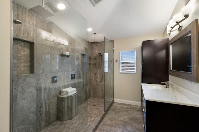 full bathroom featuring visible vents, vanity, baseboards, and a walk in shower